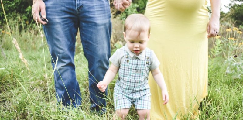 man in black tank top carrying baby in blue and white plaid button up shirt